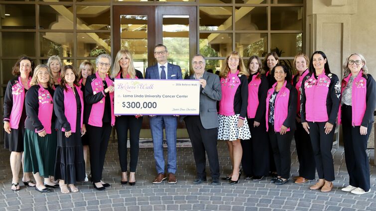 a group of people stand together holding a large check