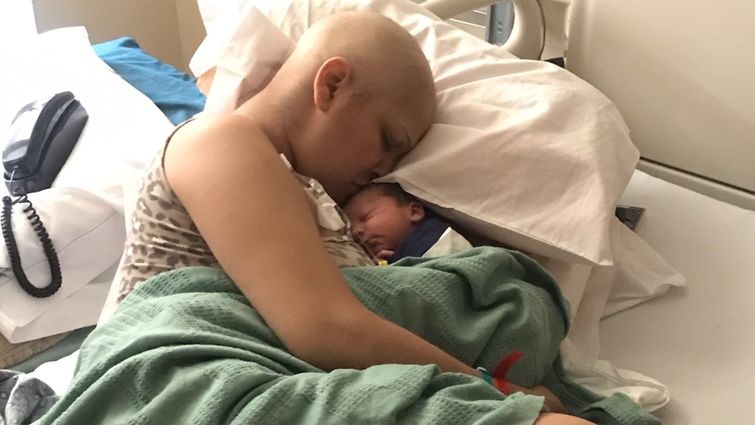 Mother kissing newborn in hospital bed