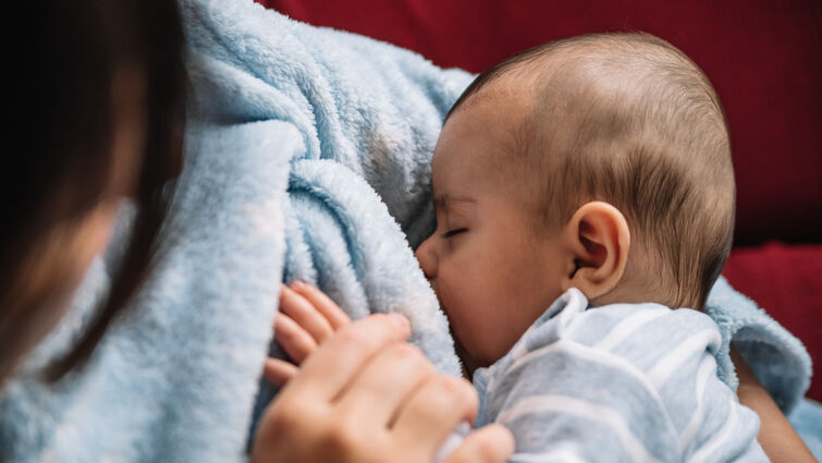 Mother breastfeeding her baby on the sofa