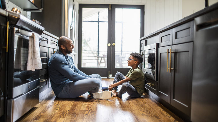 Father talking with tween son in residential kitchen 