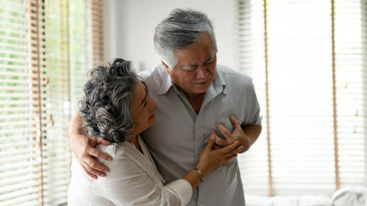 man holding his chest while woman comforts him