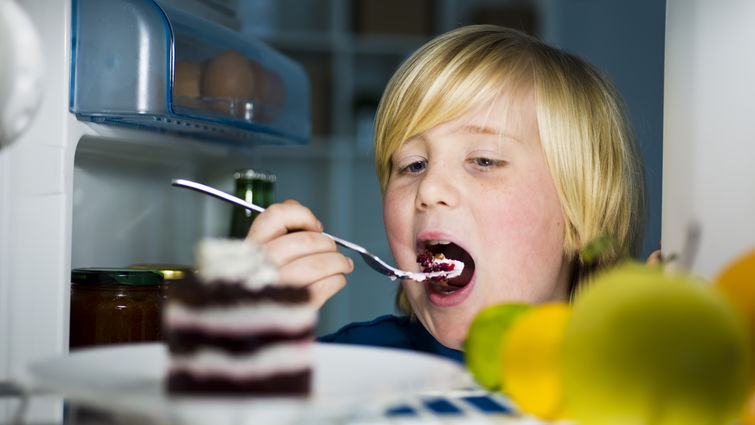 child eats cake out of the fridge