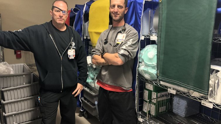 two nurses stand with medical carts called disaster carts