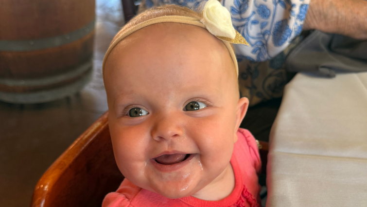 Baby sitting in high chair giggling