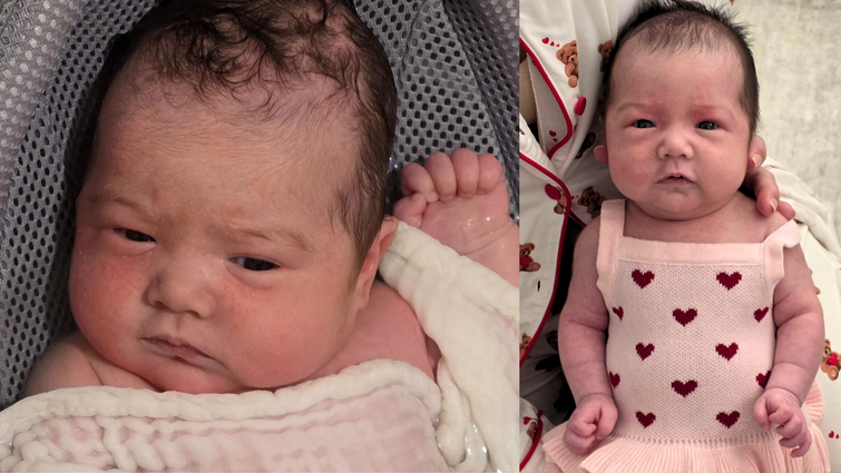 a baby in a pink dress with red hearts