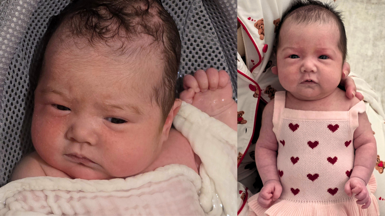 a baby in a pink dress with red hearts