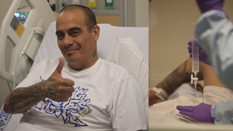 a man sitting in a hospital bed gives a thumbs up 