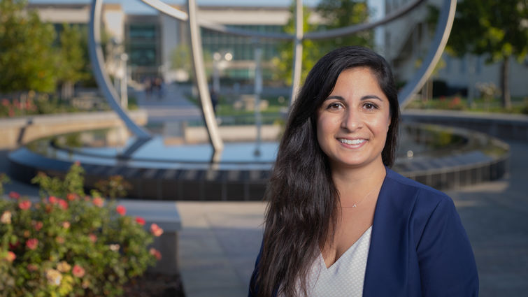 female stands outside smiling in front of fountain