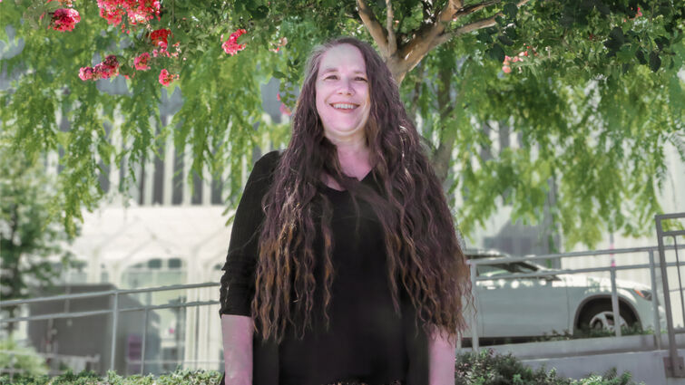 Wendy De La Pena stands outside of hospital underneath green tree