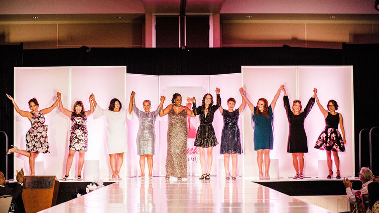 women stand on stage holding hands