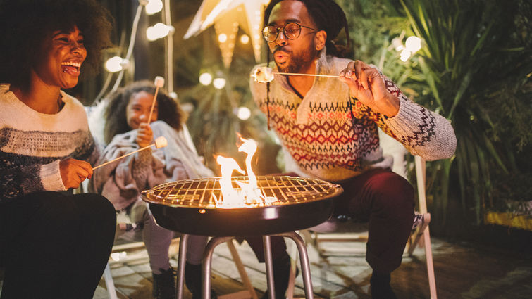 happy family roasting marshmallows in backyard fire pit