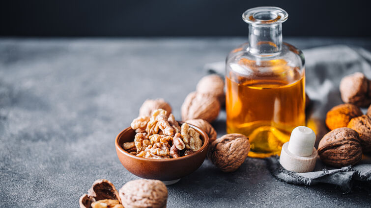 walnuts spread around a small glass bottle of oil.