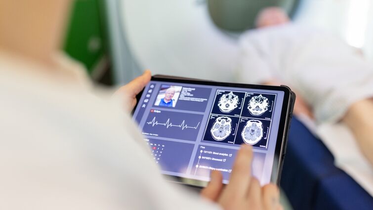 Neurologist examining patient's CAT scan images on digital table in clinic