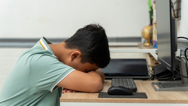 Teenage boy sleeping with his head down on a desk
