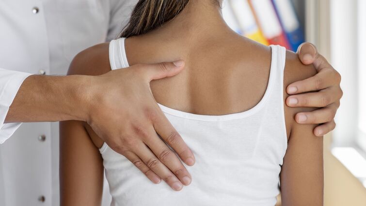Doctor doing scoliosis check on a woman's back