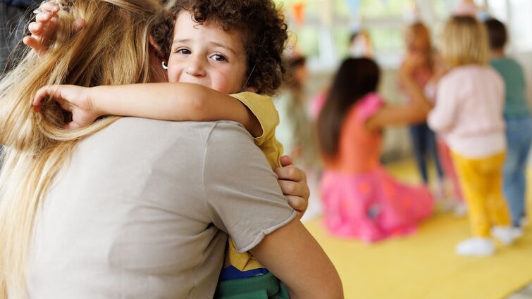 preschool-aged boy hugging mom looks sad being dropped off at school