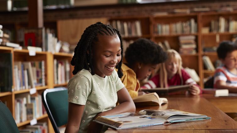 Happy girl reading book in library