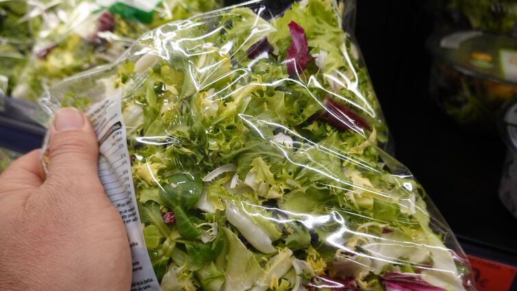 hand holding a bag of salad mix