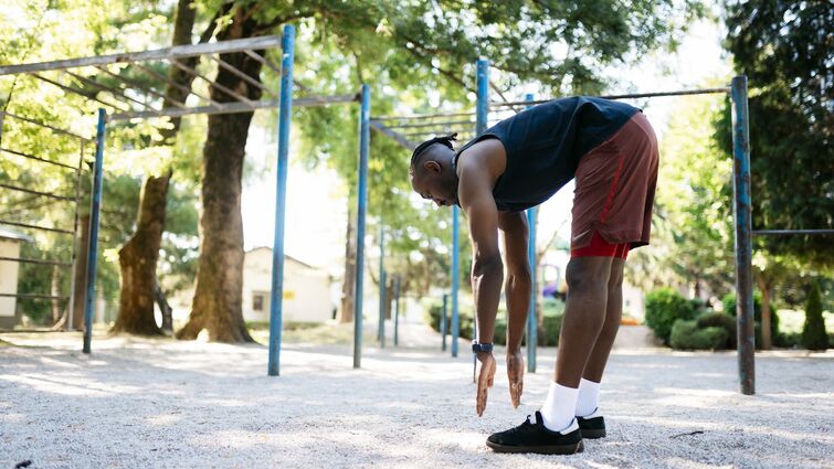 Young sportsman stretching his legs in a park