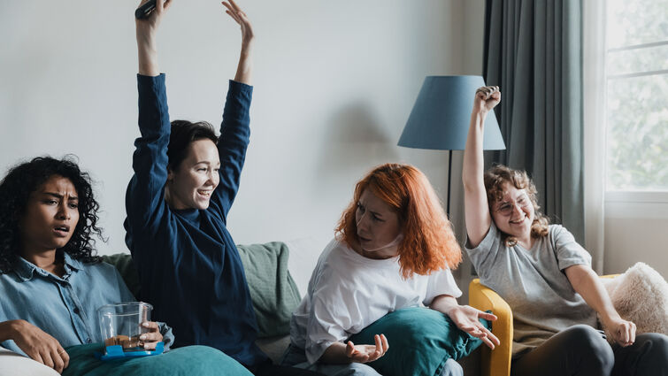 Four friends gather in a comfortable living room, animatedly watching sports. They express excitement, showing various emotions as they cheer for their favorite team.