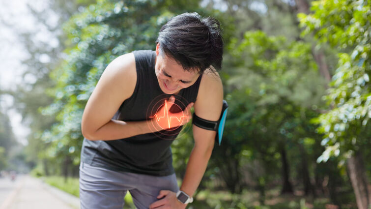 young man in park bends down by roadside and suffers from chest pain 