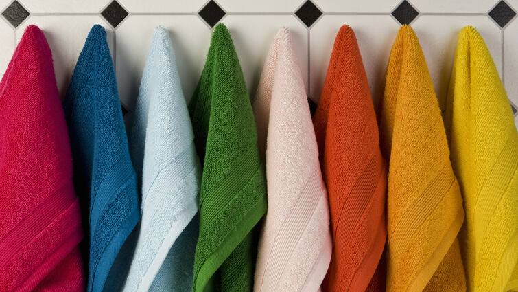 Multi colored towels hanging in a row on the wall 