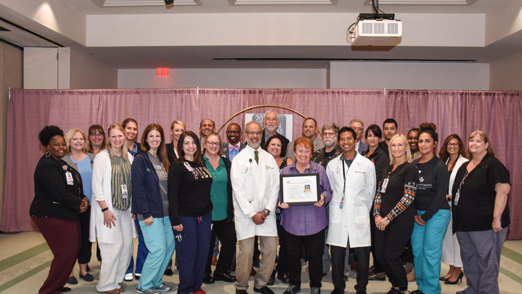 Group of doctors and staff stand in a large group holding an award