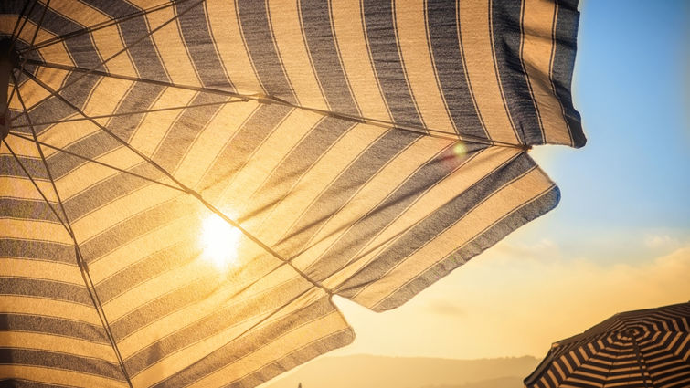 Sun shining behind the shade of a beach umbrella