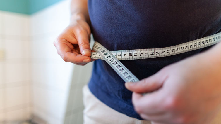 Man holding a measuring tape to his waist