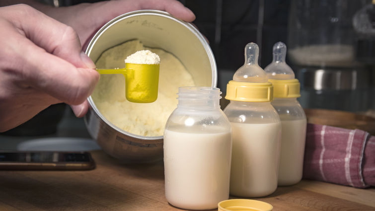 Hand holding scoop of powdered baby formula, ready to mix in bottles stock photo