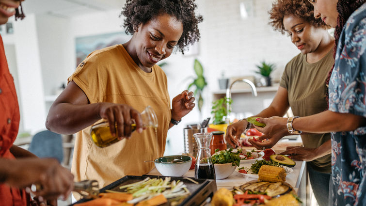 Group of female friends making vegetarian lunch in the kitchen at apartment together