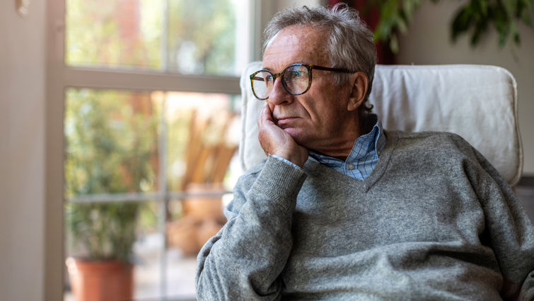 Sad white man staring out the window lost in his thoughts (stock image)