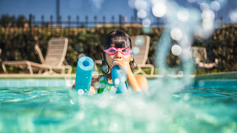 child in goggles playing in pool with foam floaty