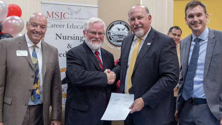 Dr. Carter and Dr. Schultz shake hands after signing the agreement