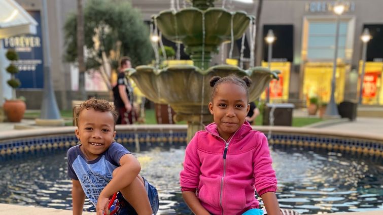 Young Black girl and boy sitting on a fountain edge