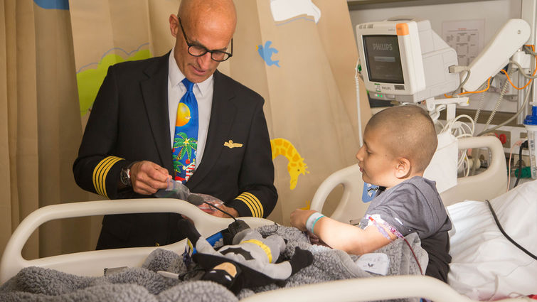male pilot gives gifts to cancer patient