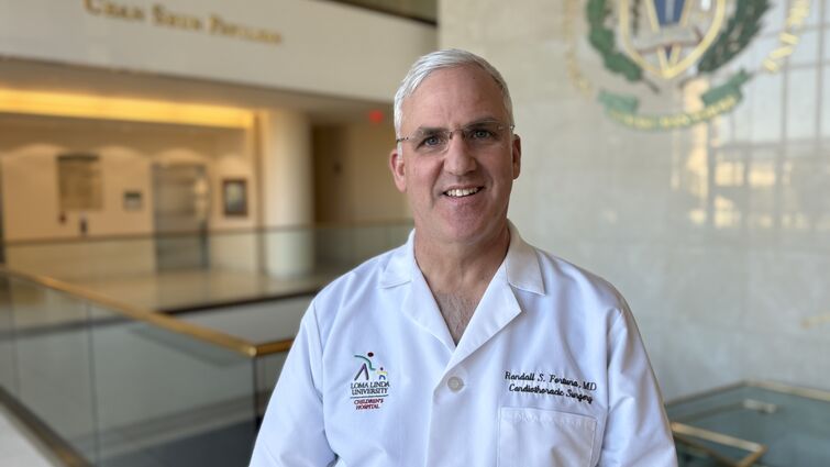 Dr. Randall Fortuna wearing white coat in hallway smiling