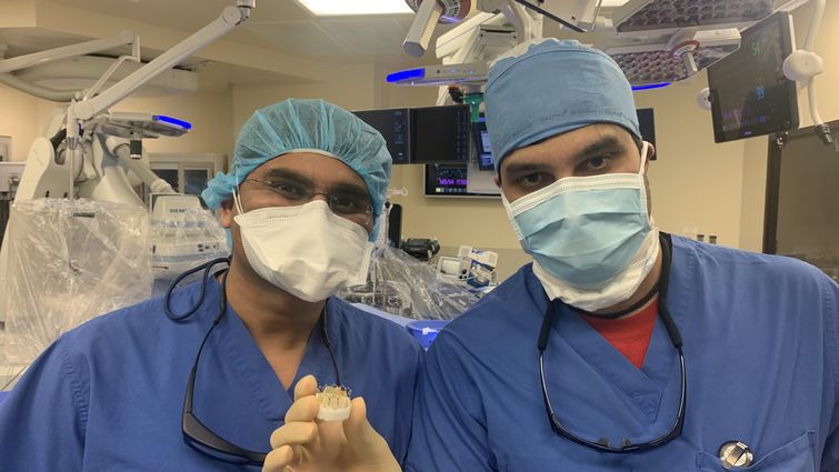 Cardiologists Harit Desai, MD and Niraj Parekh, MD and hold up an artificial heart valve used to replace diseased valves of patients during TAVR (transcatheter aortic valve replacement) procedures. 