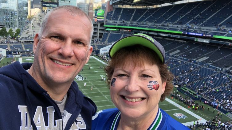 From left: Ed Koehn and his wife, Karen, take a selfie in a Seattle stadium to watch their favorite football teams — Cowboys and Seahawks — play in October 2018.