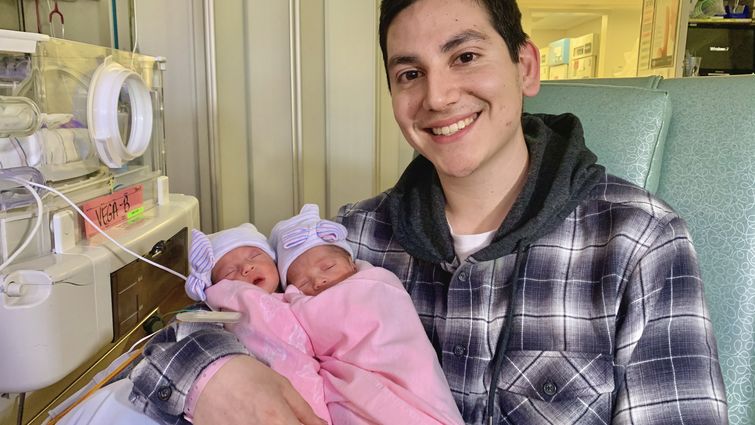 young father holds twin girls