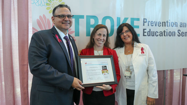 Three people hold an award