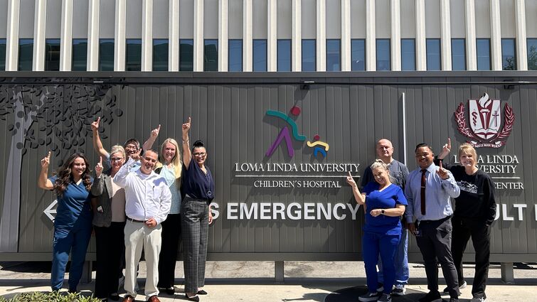 group of medical staff celebrating their recognirion outside in front of Emergency room signage
