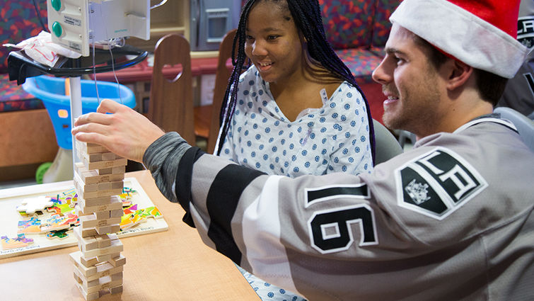 Ontario Reign CH Visit hockey player plays jenga with teenage female patient