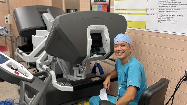 Dr. Le sits at the surgical robot's console,  where he performs minimally invasive chest surgeries on patients