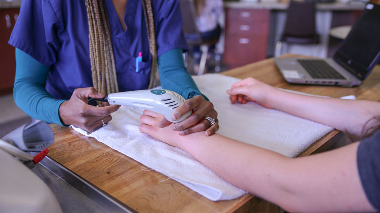 Hand therapist uses ultrasound therapy machine on patient