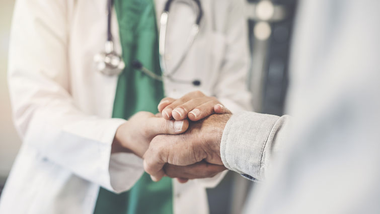 unidentified doctor holds hand of unidentified patient