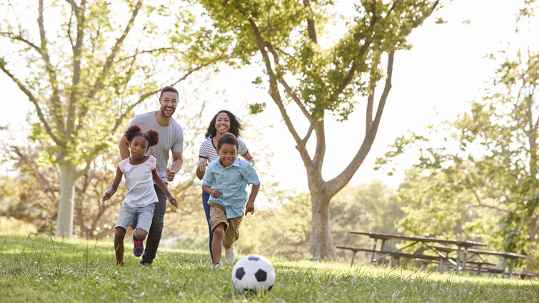 Family Playing Soccer In Park Together