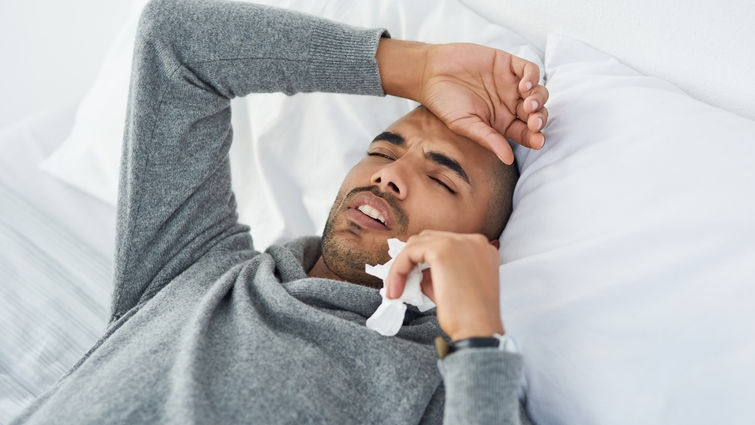 Man lying in bed with a headache