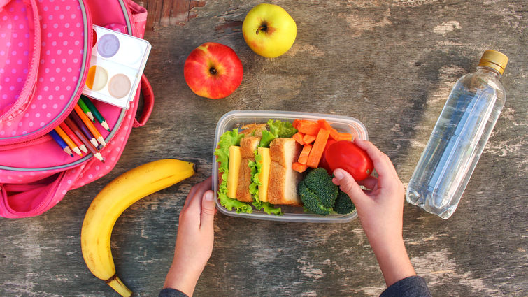 Sandwiches, fruits and vegetables in food box, backpack on old wooden background. Concept of child eating at school. Top view. Flat lay.