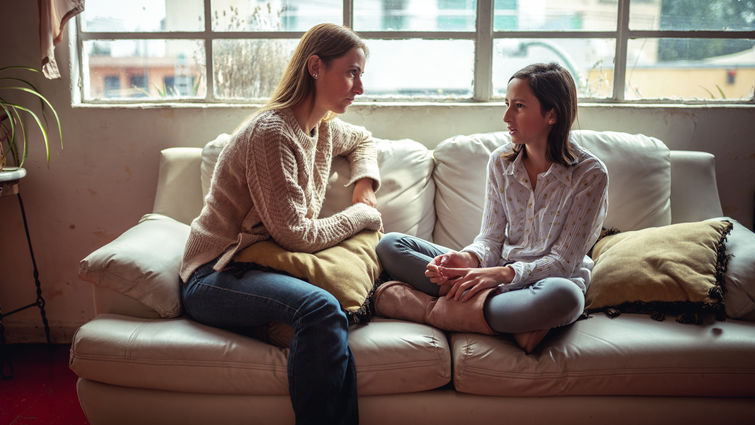 mother and daughter sitting on couch having a talk